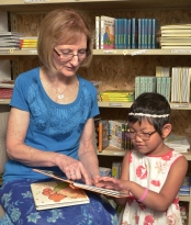Photo of Debra Bonde and a little girl reading braille together