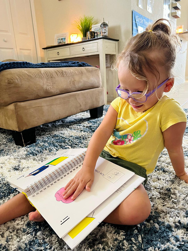 Cora, 3 Photo of a young girl touching a braille book