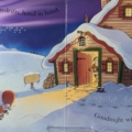 Interior spread of Goodnight Santa with print words, braille, and an illustration of two children pulling a sled through snow.