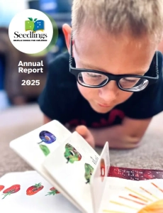 Annual report cover 2025 A young boy with glasses reading a Seedlings board book